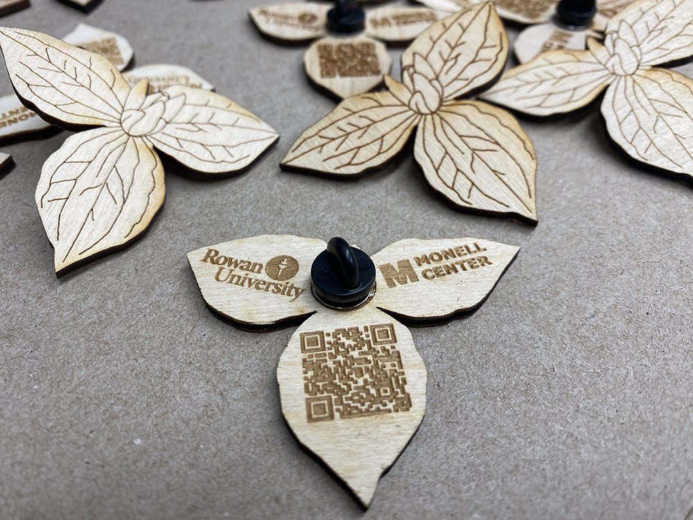 Wooden pins in the shape of a plant with a QR code and Rowan University logo