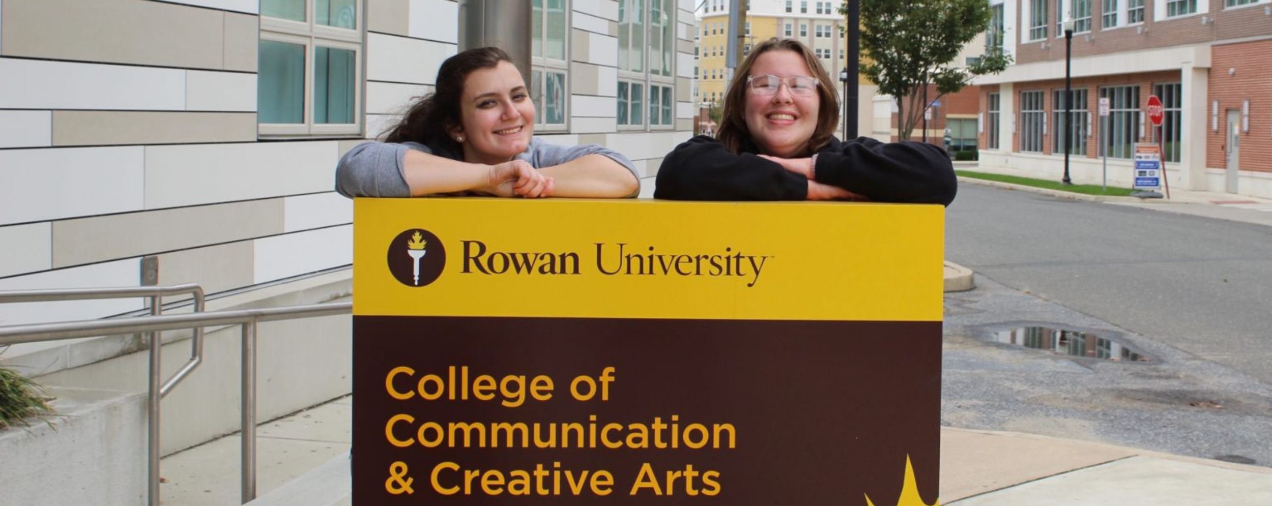 Two students in front of the Edelman CCCA signage